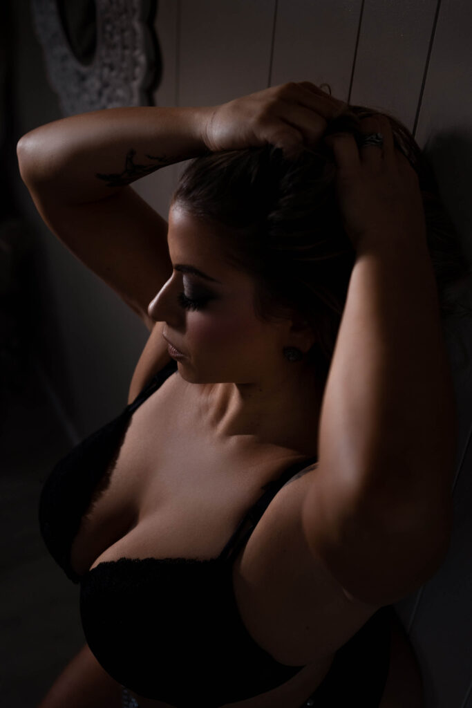Luxury Boudir Image of a woman looking dwon in a black bra. Image atken by Boudoir by Laurette